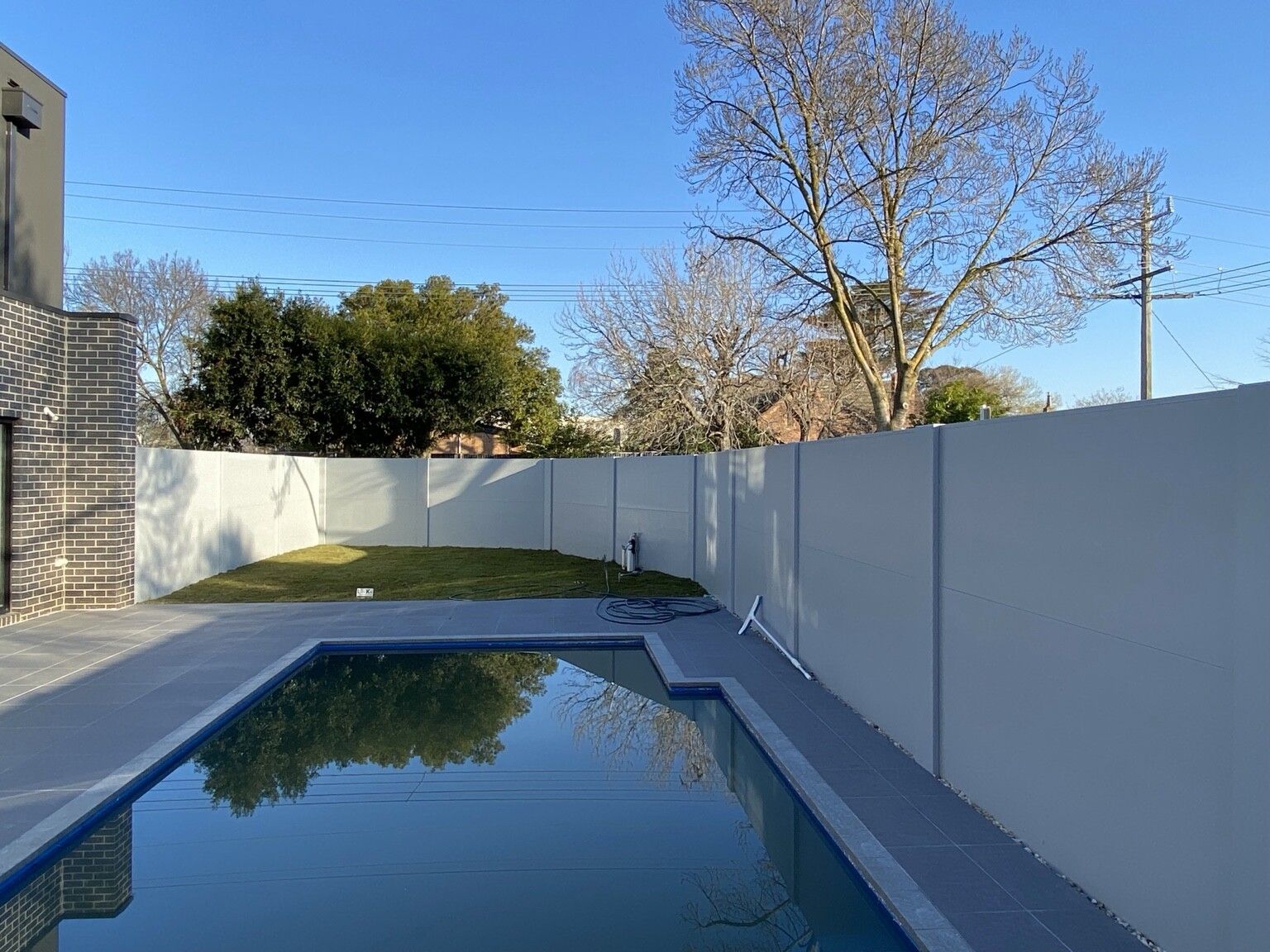 A grey VogueWall along the boundary of a pool and lawn, Ashburton.