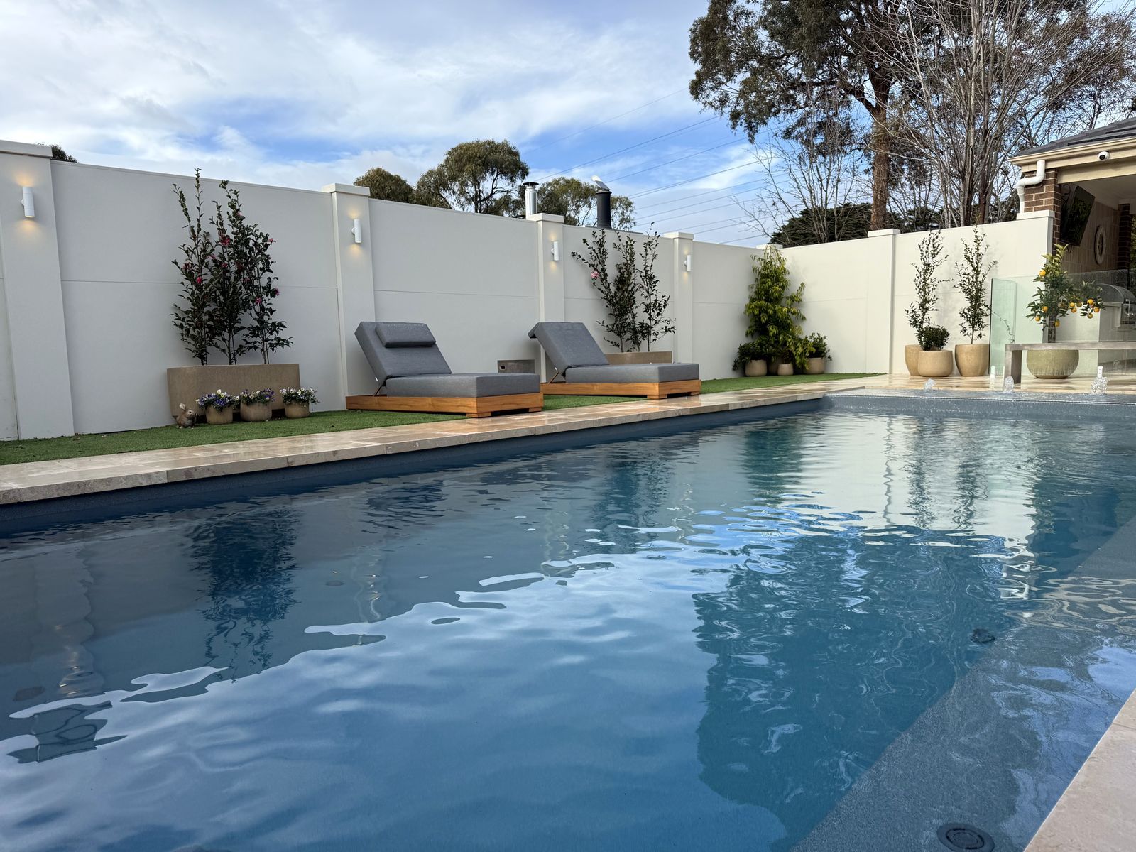 EstateWall enclosing a pool and entertaining area, with lights on the wall posts and planting along the base, Diamond Creek.