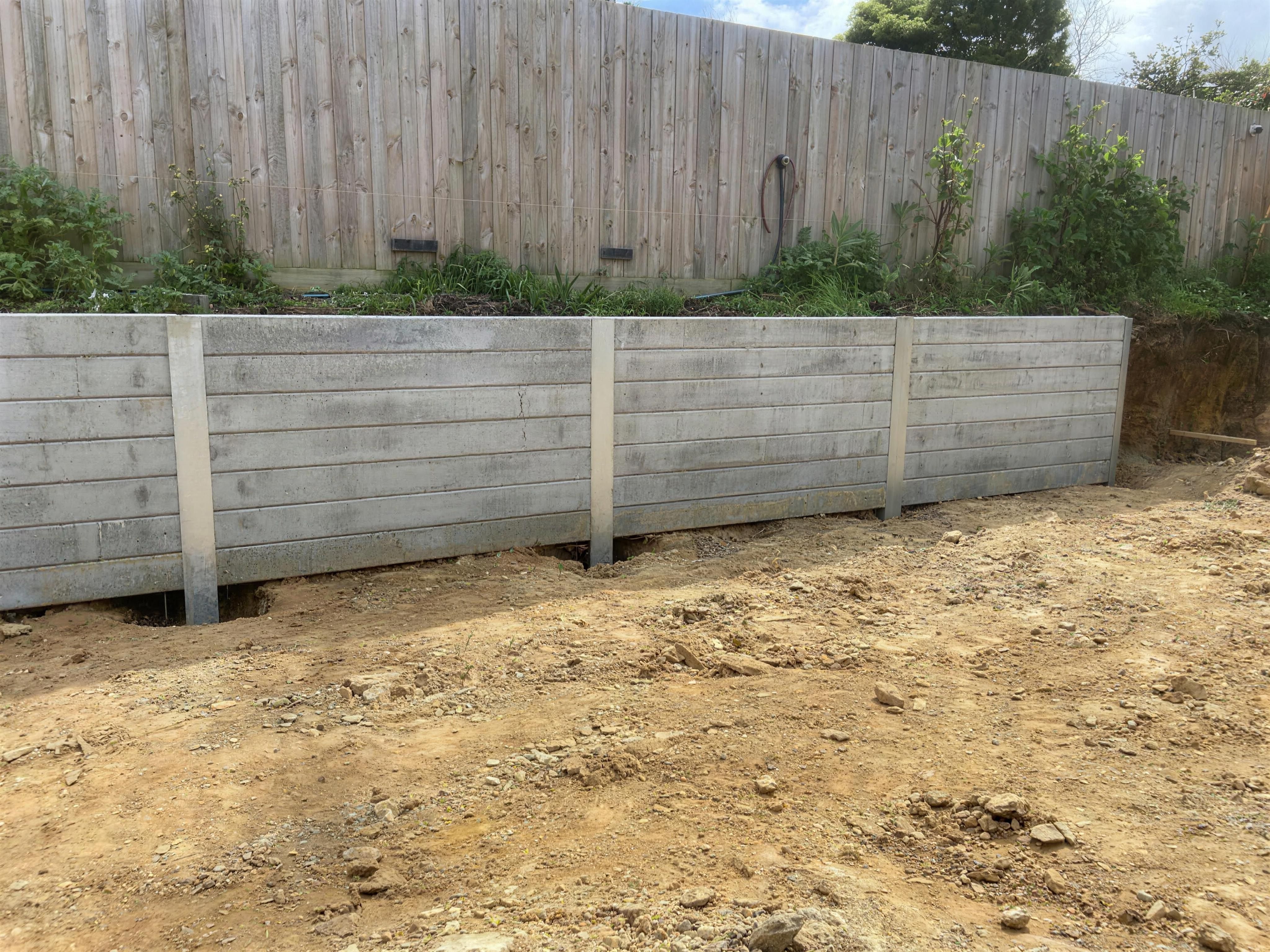 A run of concrete sleeper retaining wall on steel posts holding back a garden bed below a timber paling fence, Mount Eliza.